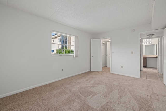 unfurnished bedroom with a walk in closet, light colored carpet, and a textured ceiling