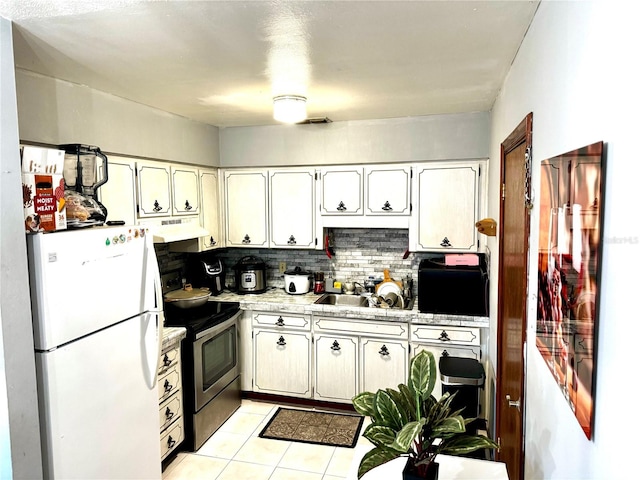 kitchen with white refrigerator, white cabinetry, and stainless steel range with electric cooktop