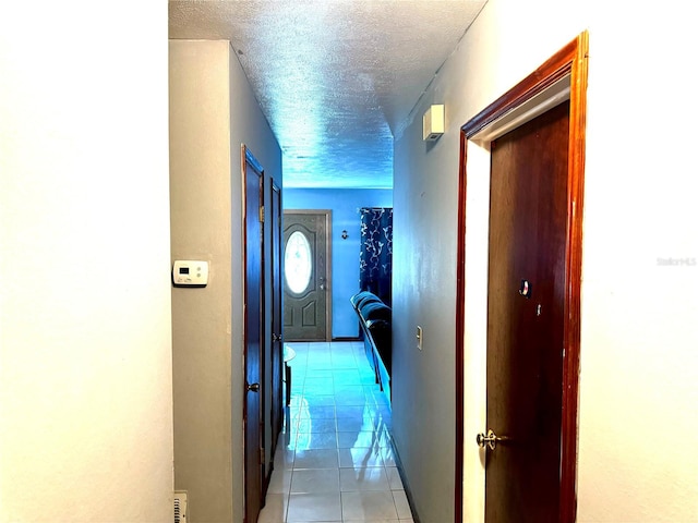 hall featuring light tile patterned floors and a textured ceiling