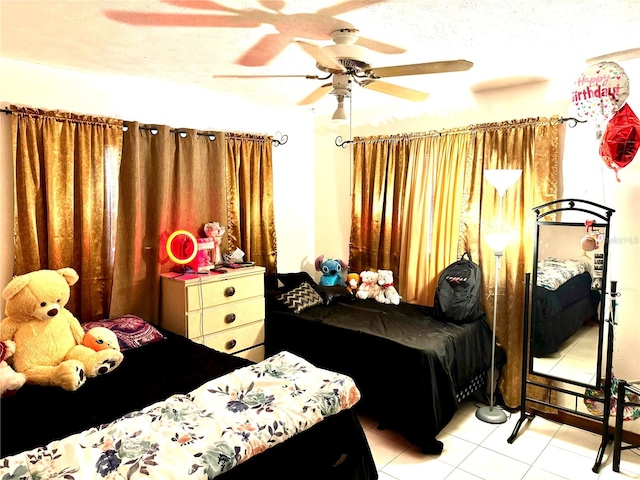 bedroom featuring a textured ceiling, light tile patterned floors, and ceiling fan