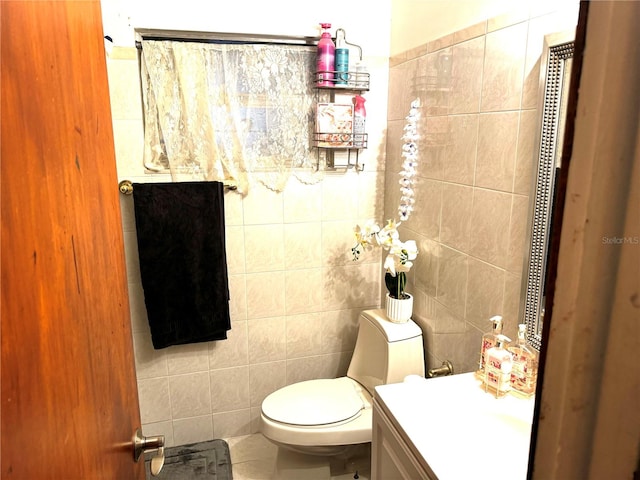 bathroom featuring vanity, toilet, and tile walls