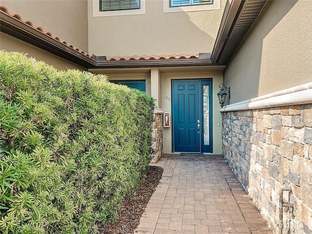 entrance to property with a tile roof and stucco siding