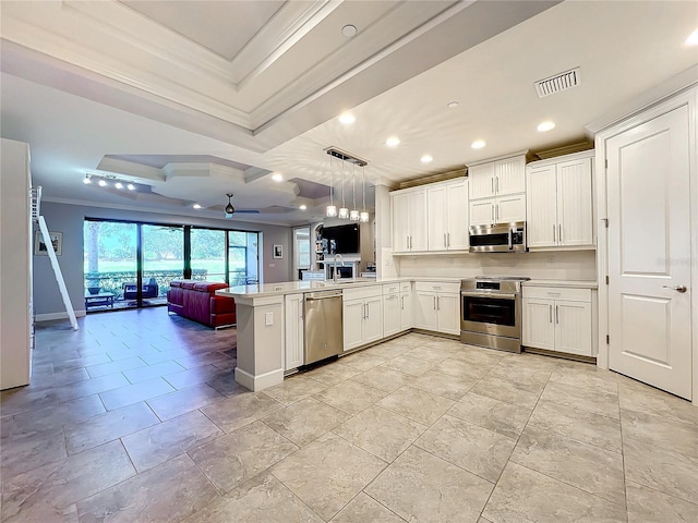 kitchen featuring pendant lighting, light countertops, appliances with stainless steel finishes, open floor plan, and a peninsula