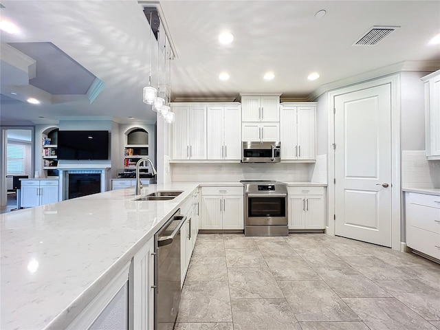 kitchen with appliances with stainless steel finishes, sink, crown molding, light stone countertops, and white cabinets