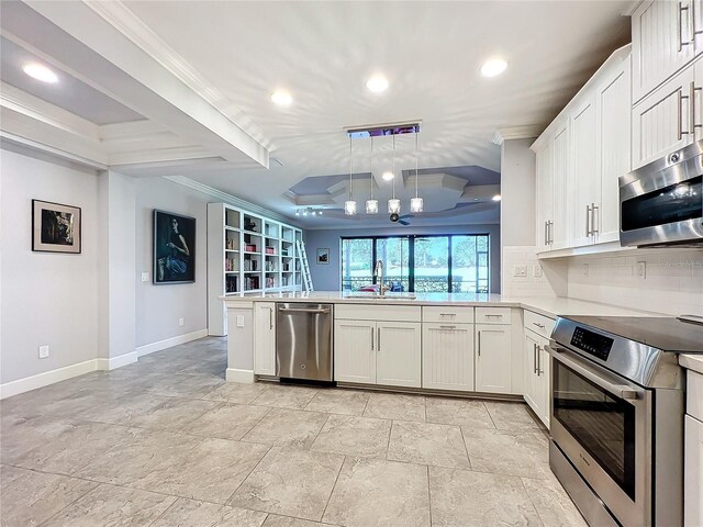 kitchen featuring stainless steel appliances, decorative backsplash, sink, a raised ceiling, and kitchen peninsula