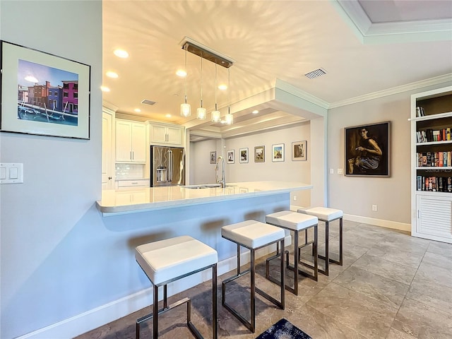 kitchen featuring high quality fridge, a breakfast bar area, visible vents, light countertops, and hanging light fixtures