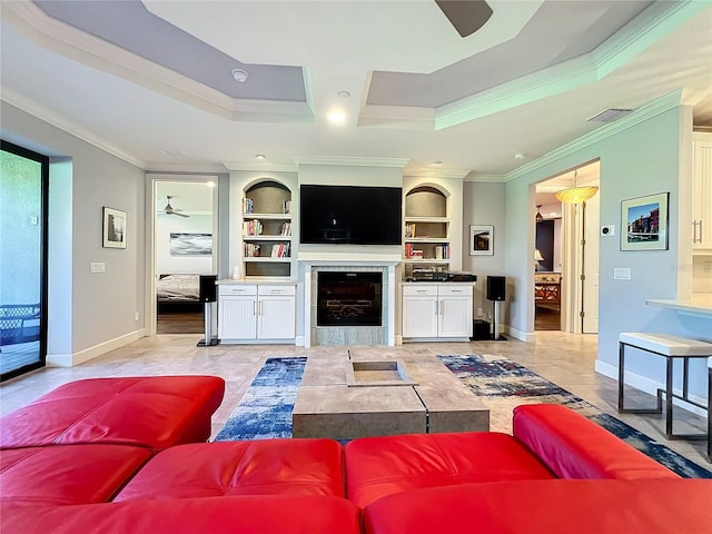 tiled living room featuring ceiling fan, a raised ceiling, crown molding, and a tile fireplace