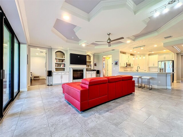 living room with light tile patterned floors, ornamental molding, coffered ceiling, ceiling fan, and a raised ceiling