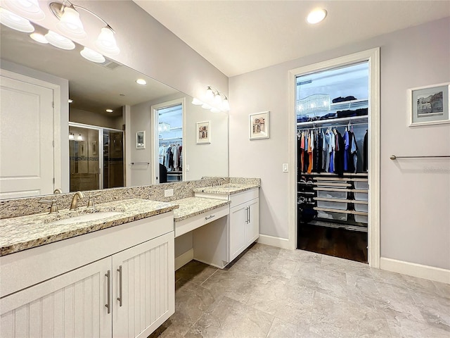 full bath featuring a shower stall, baseboards, a walk in closet, and vanity