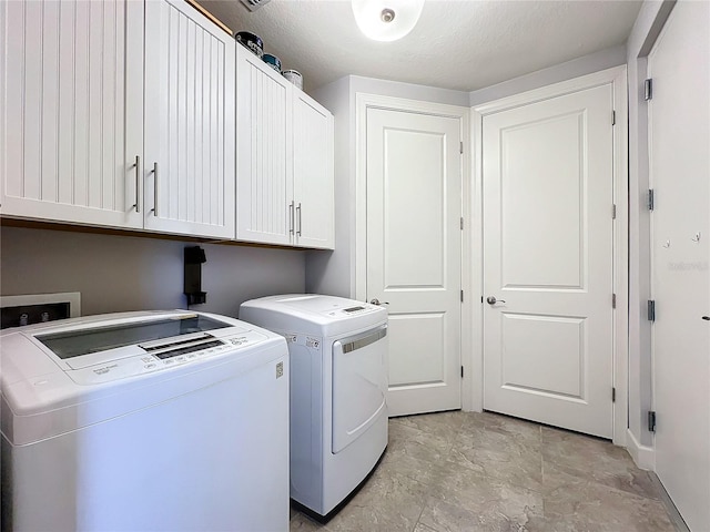 clothes washing area with independent washer and dryer, light tile patterned floors, and cabinets