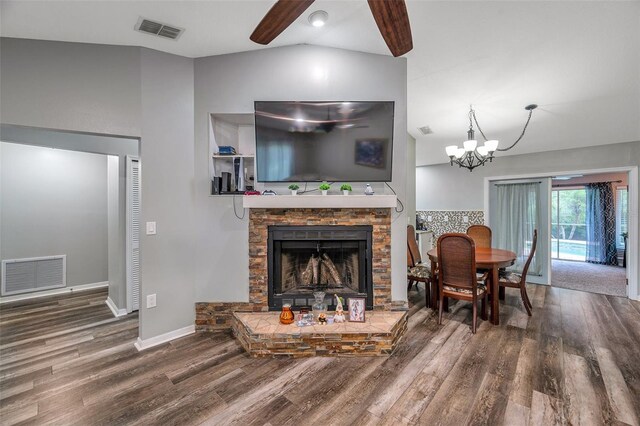 living room with a fireplace, vaulted ceiling, an inviting chandelier, and wood-type flooring