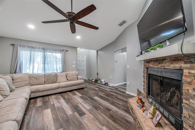 living room featuring ceiling fan, a stone fireplace, and dark hardwood / wood-style floors