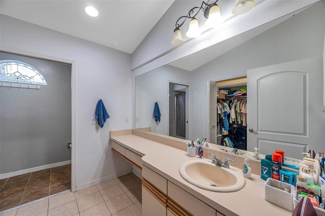 bathroom with vaulted ceiling, vanity, and tile patterned floors