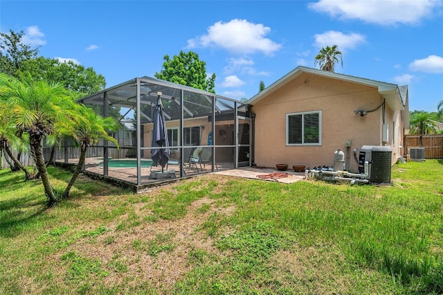 rear view of house featuring glass enclosure, a patio area, a fenced in pool, a yard, and central air condition unit