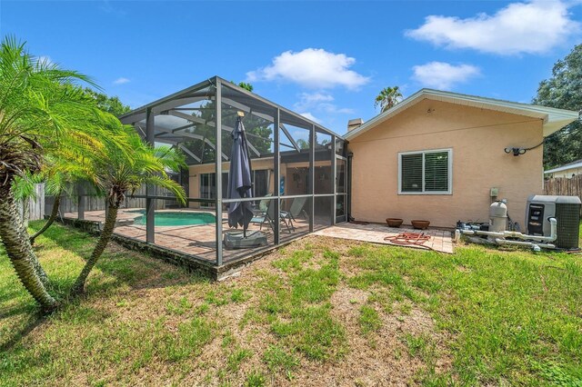 rear view of property featuring a yard, a fenced in pool, a patio area, and a lanai