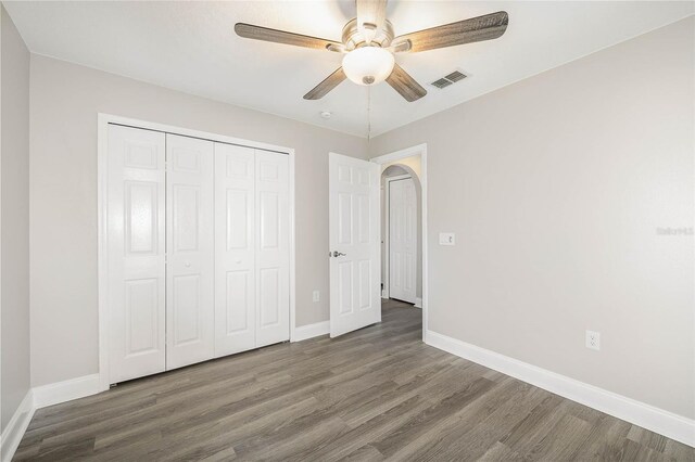 unfurnished bedroom with ceiling fan, a closet, and wood-type flooring