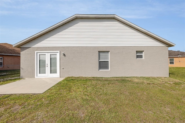 back of property with a lawn and french doors