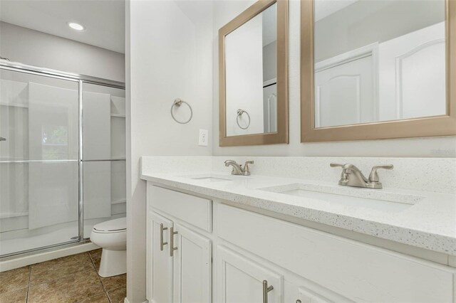 bathroom with a stall shower, a sink, toilet, and double vanity