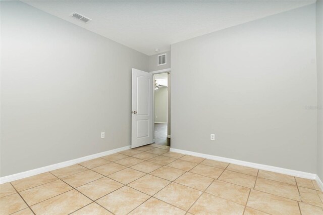 empty room with light tile patterned floors, visible vents, and baseboards