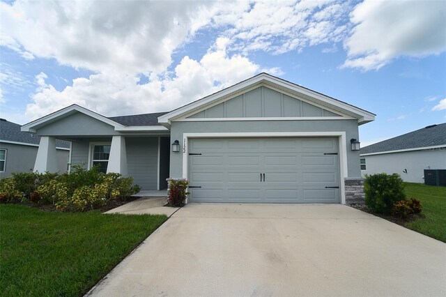 view of front of property with central air condition unit, a garage, and a front lawn