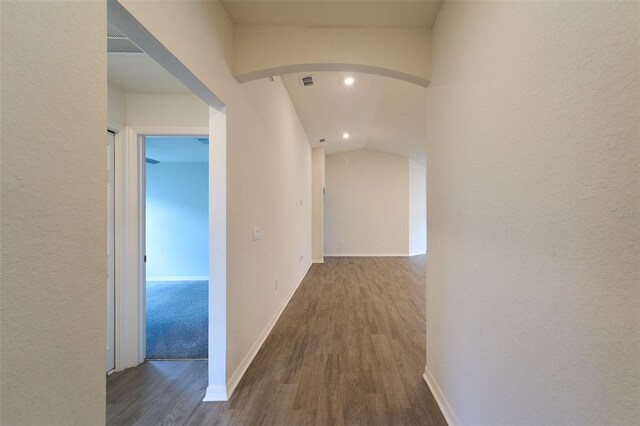 hallway featuring dark wood-type flooring and vaulted ceiling