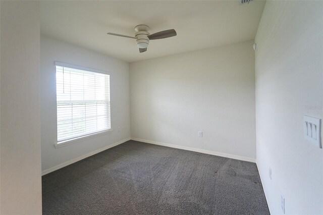 unfurnished room with ceiling fan and dark carpet