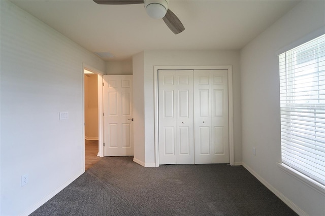 unfurnished bedroom featuring ceiling fan, a closet, and dark colored carpet