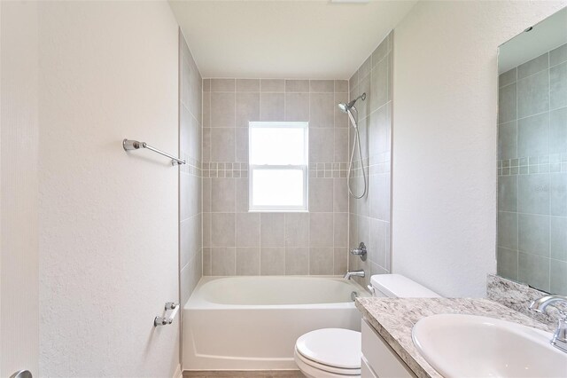 full bathroom featuring tiled shower / bath, vanity, and toilet