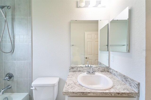 full bathroom featuring tiled shower / bath combo, toilet, and vanity