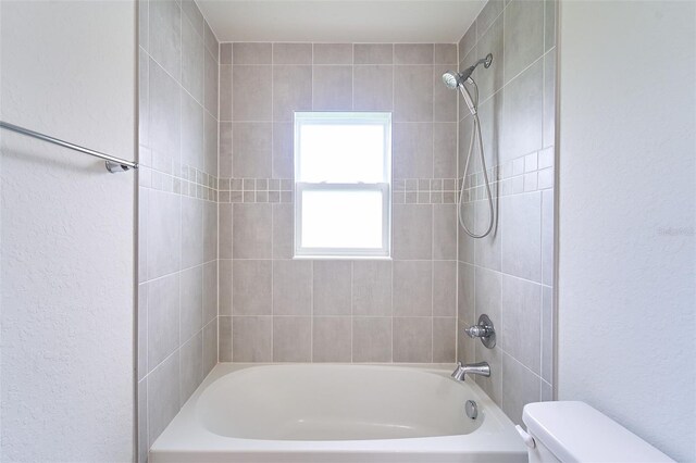 bathroom featuring tiled shower / bath and toilet