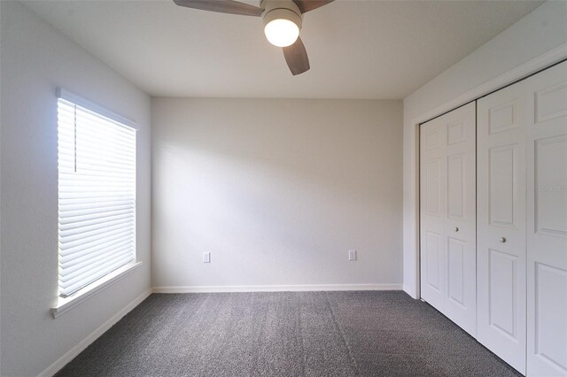 unfurnished bedroom with ceiling fan, a closet, carpet, and multiple windows