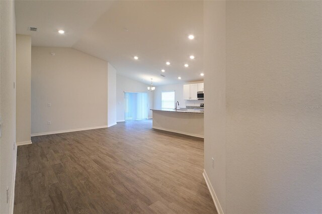 unfurnished living room featuring sink, vaulted ceiling, and light hardwood / wood-style flooring