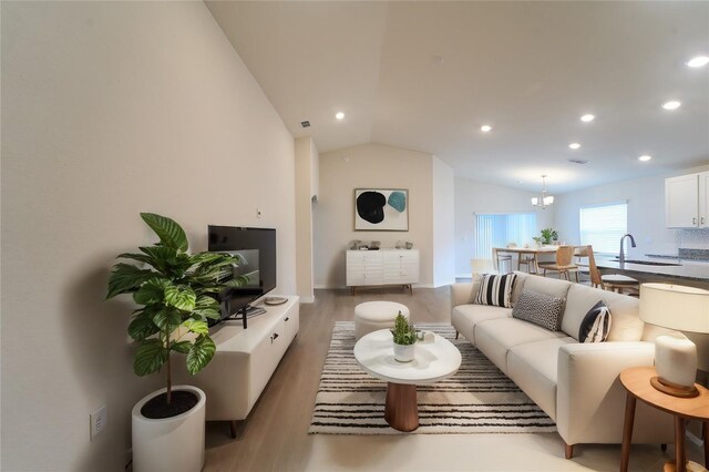 living room with vaulted ceiling, sink, hardwood / wood-style flooring, and a chandelier