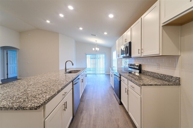 kitchen with tasteful backsplash, vaulted ceiling, white cabinetry, appliances with stainless steel finishes, and hardwood / wood-style flooring