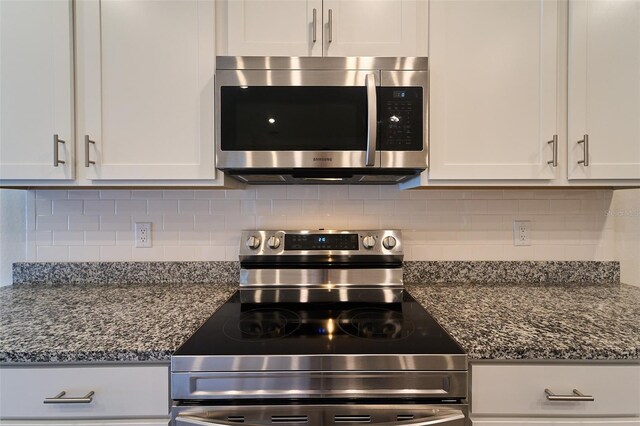 kitchen featuring white cabinets, dark stone counters, backsplash, and stainless steel appliances