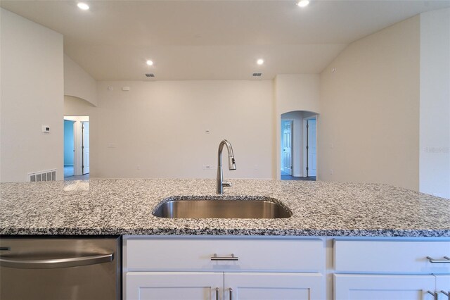 kitchen with stainless steel dishwasher, sink, light stone countertops, and white cabinets