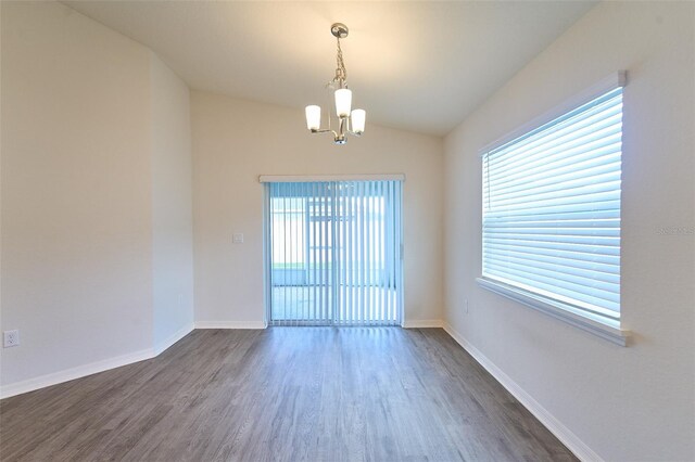 empty room with dark hardwood / wood-style floors, vaulted ceiling, and a notable chandelier