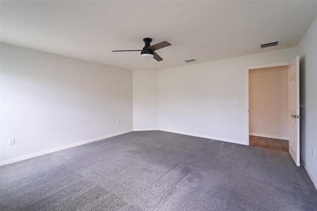 spare room featuring ceiling fan and dark carpet