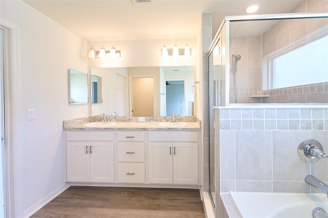 bathroom featuring plus walk in shower, vanity, and wood-type flooring