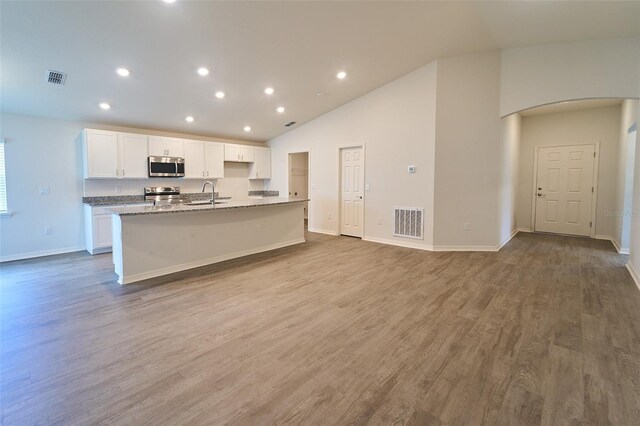 kitchen featuring stainless steel appliances, hardwood / wood-style floors, sink, a center island with sink, and white cabinets