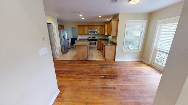 kitchen with a kitchen island, sink, light wood-type flooring, and stainless steel appliances