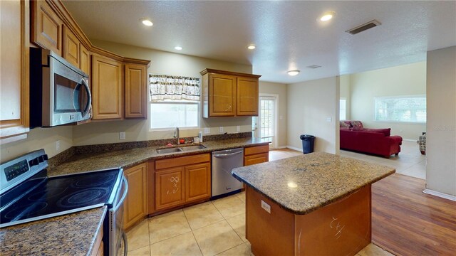 kitchen featuring sink, a kitchen island, a healthy amount of sunlight, and appliances with stainless steel finishes