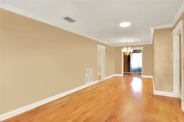 empty room featuring crown molding, a textured ceiling, light hardwood / wood-style flooring, and a notable chandelier