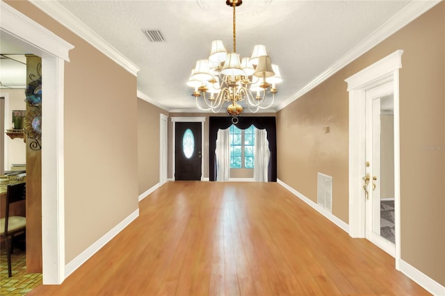 entryway featuring crown molding, hardwood / wood-style floors, a notable chandelier, and a textured ceiling