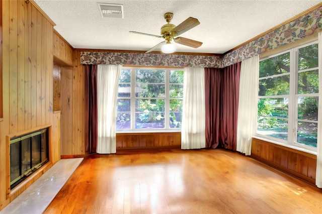 unfurnished living room with ceiling fan, a healthy amount of sunlight, light hardwood / wood-style floors, and a textured ceiling