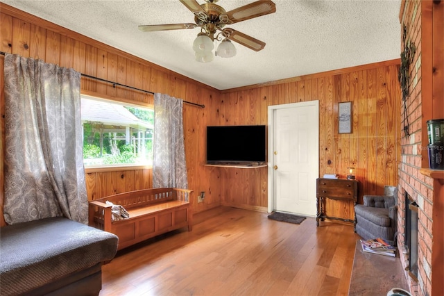 living room featuring wood-type flooring, a textured ceiling, and wood walls