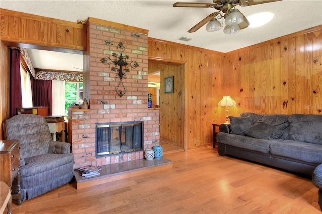 living room featuring hardwood / wood-style flooring, a fireplace, wooden walls, and a textured ceiling