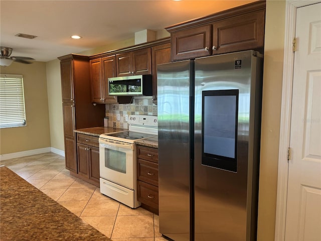 kitchen with ceiling fan, tasteful backsplash, dark stone countertops, light tile patterned flooring, and stainless steel appliances