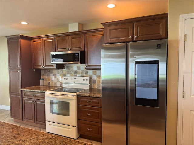 kitchen with light tile patterned floors, appliances with stainless steel finishes, tasteful backsplash, and dark stone counters