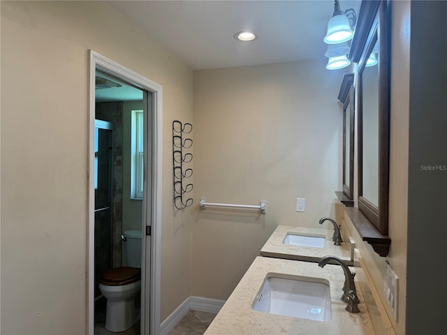 full bath featuring toilet, double vanity, baseboards, and a sink